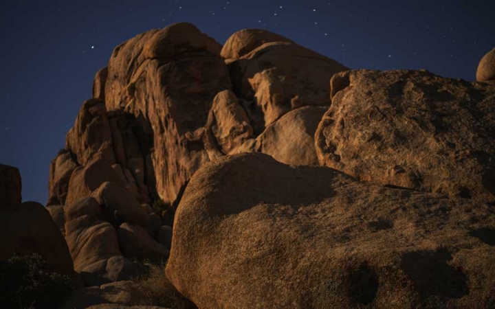 Large boulders appear in front of a dark blue, starry sky.